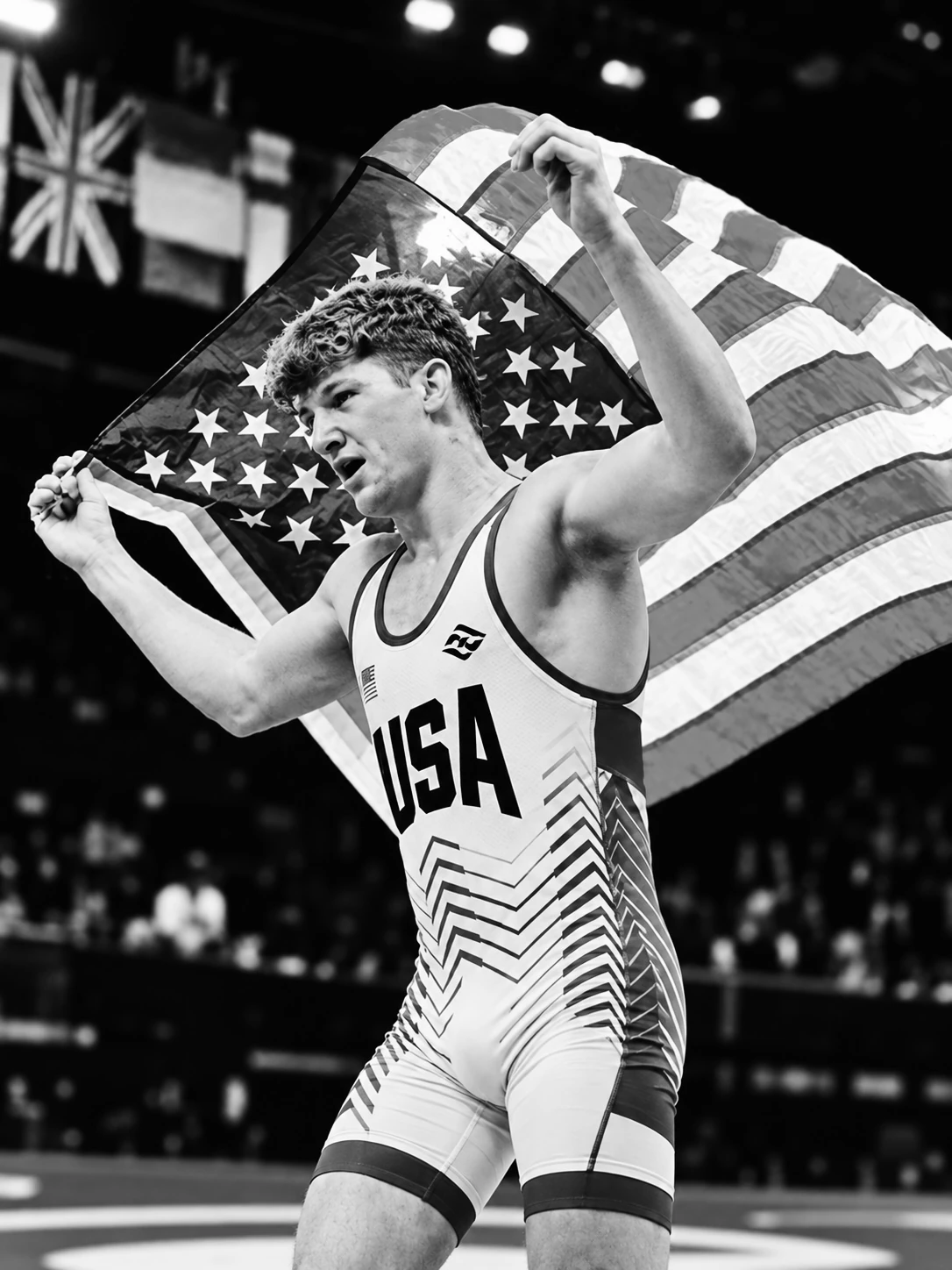 U.S. men’s freestyle wrestler holding an American flag overhead in the arena