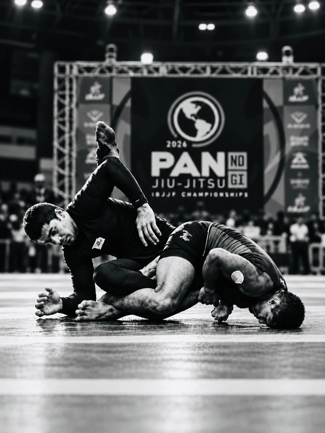 Two no-gi grapplers tangled on the mat in front of the 2026 Pan No-Gi Jiu-Jitsu banner